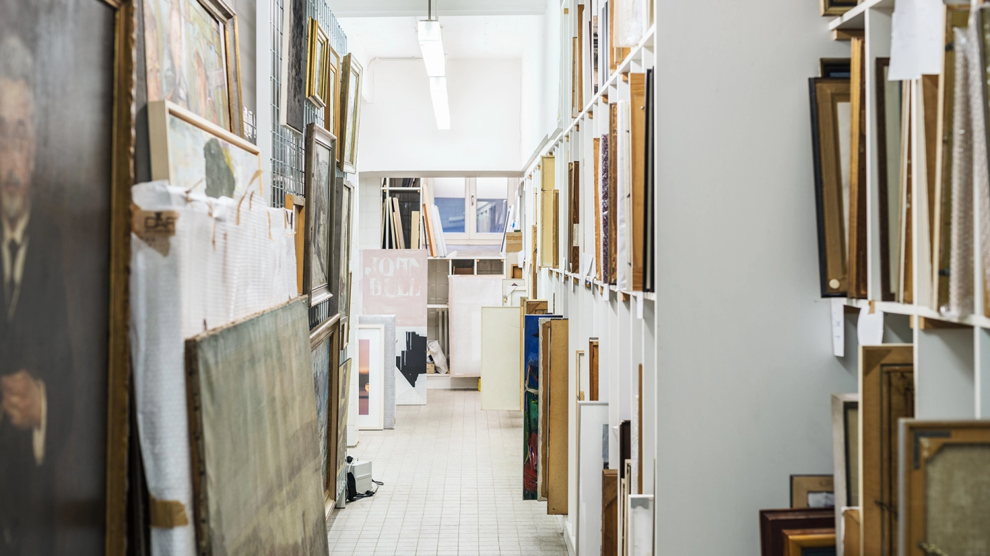 Blick in die Städtische Kunstsammlung. Ein Gang mit Regalen auf beiden Seiten, die mit Bildern in verschiedenen Größen befüllt sind.